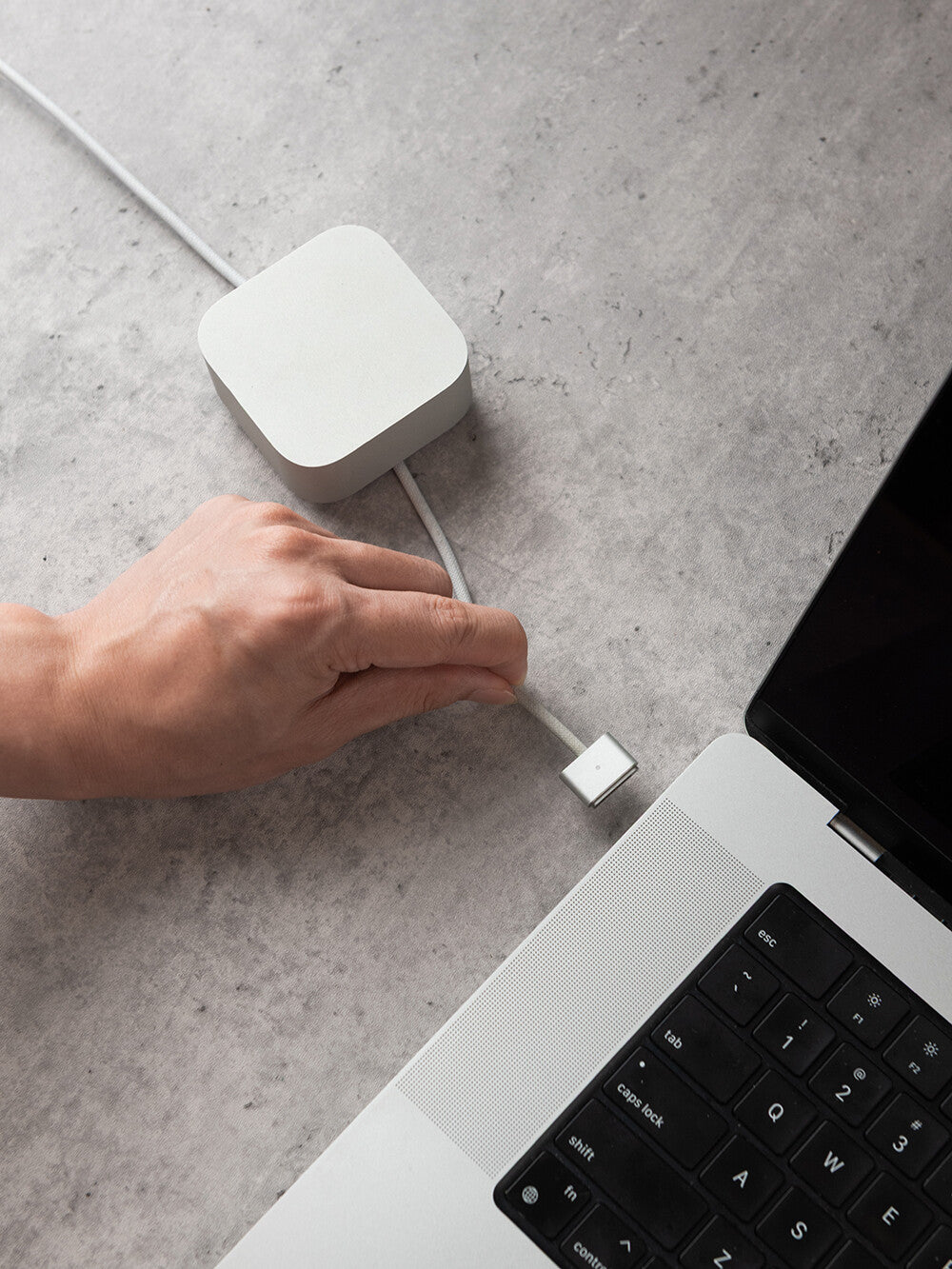 KOKOGOL Cube Mini Cable Organizer on concrete desk with MagSafe cable plugged into MacBook Pro